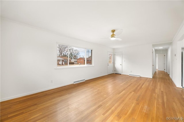 interior space with attic access, baseboards, a ceiling fan, a baseboard radiator, and light wood-type flooring