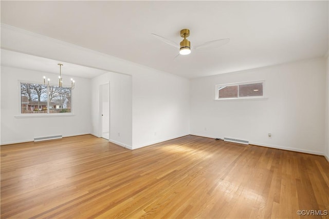 empty room featuring a baseboard radiator, ceiling fan with notable chandelier, visible vents, baseboards, and light wood finished floors