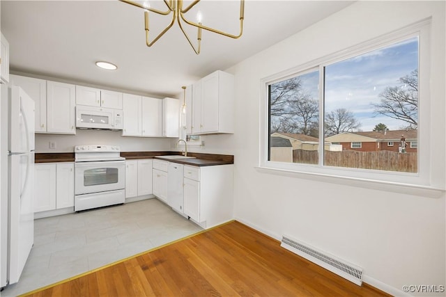 kitchen featuring dark countertops, white appliances, visible vents, and white cabinetry