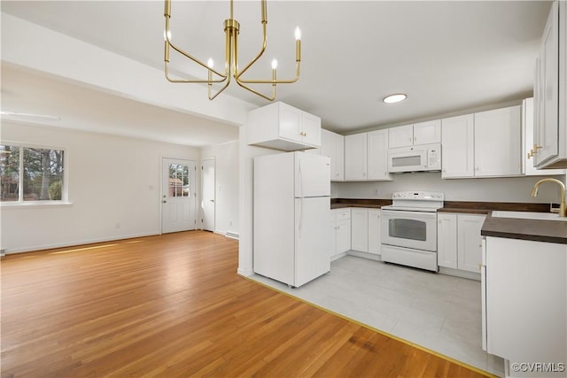 kitchen with white appliances, dark countertops, a sink, and a wealth of natural light