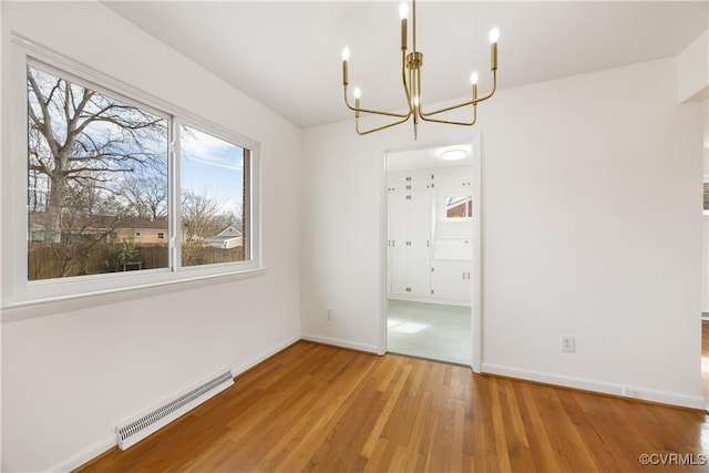 unfurnished bedroom featuring baseboards, an inviting chandelier, and wood finished floors