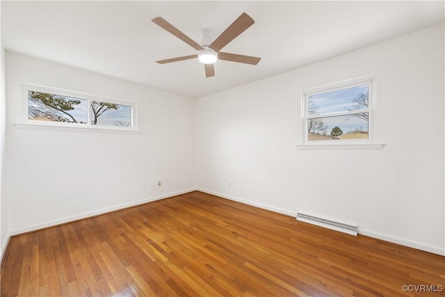 empty room featuring wood-type flooring, visible vents, ceiling fan, and baseboards