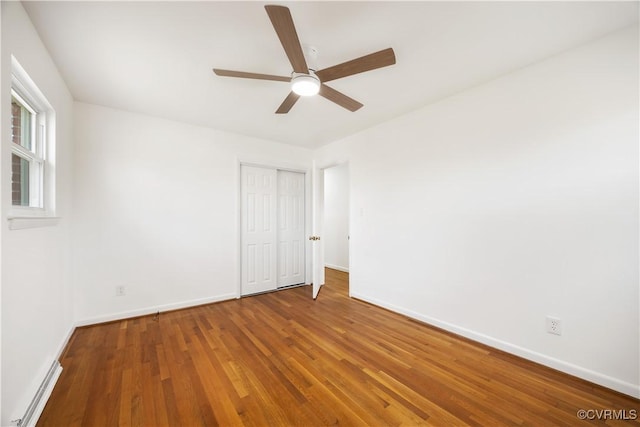 unfurnished bedroom featuring a closet, wood finished floors, a ceiling fan, and baseboards