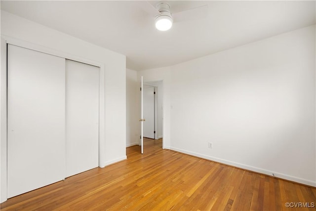 unfurnished bedroom featuring light wood-type flooring, baseboards, and a closet