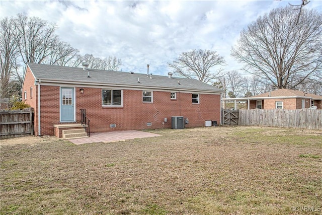 back of house featuring brick siding, crawl space, a fenced backyard, and a lawn