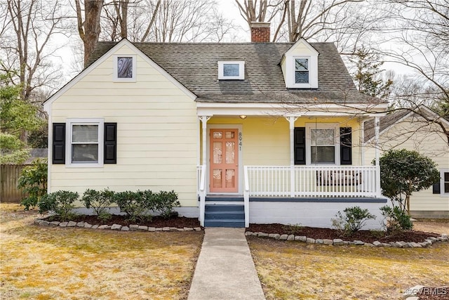 cape cod home with a porch, a shingled roof, fence, a front lawn, and a chimney