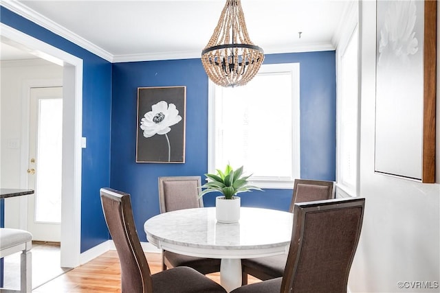 dining room with a chandelier, ornamental molding, wood finished floors, and baseboards