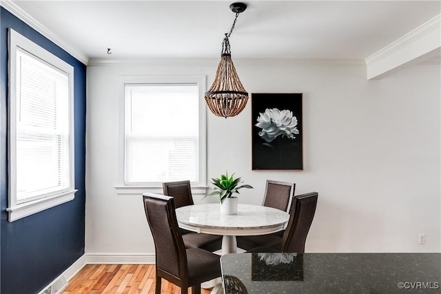 dining space with light wood finished floors, ornamental molding, and a wealth of natural light