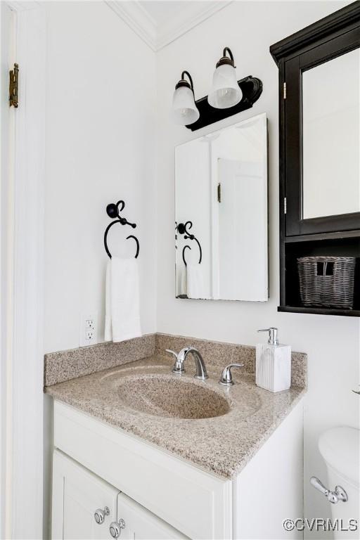 half bathroom with crown molding, vanity, and toilet