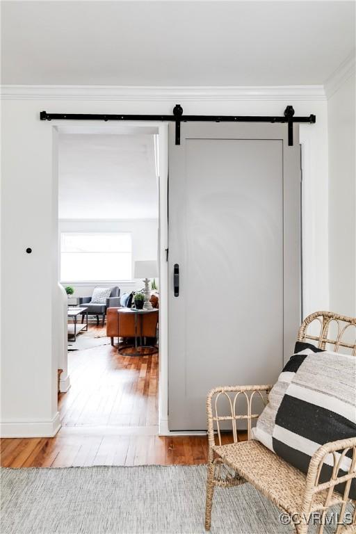 interior space featuring a barn door, crown molding, and wood finished floors