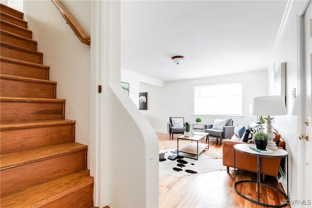 stairs with ornamental molding and wood finished floors