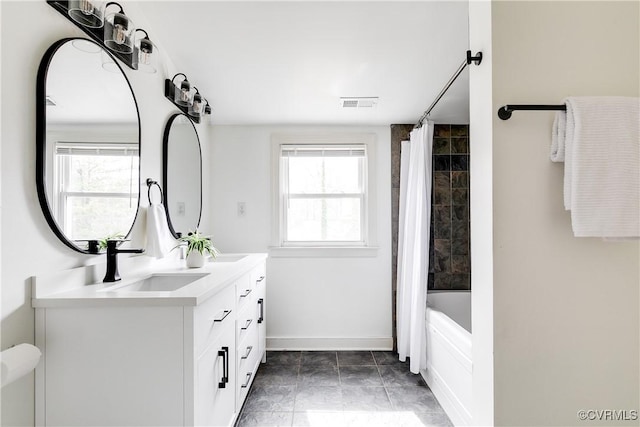 full bath featuring double vanity, shower / tub combo, baseboards, visible vents, and a sink