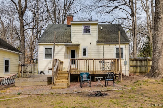 rear view of property with roof with shingles, a chimney, fence, and a wooden deck