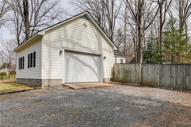 detached garage featuring gravel driveway and fence