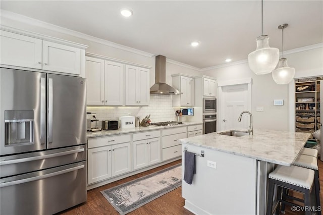 kitchen featuring dark wood finished floors, stainless steel appliances, ornamental molding, a sink, and wall chimney range hood