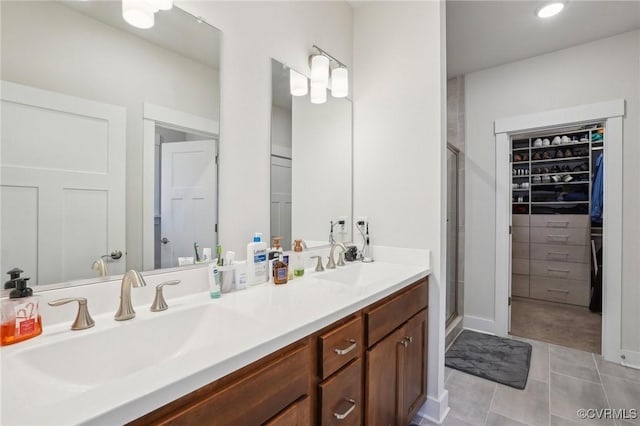 bathroom with a stall shower, tile patterned floors, a sink, and double vanity