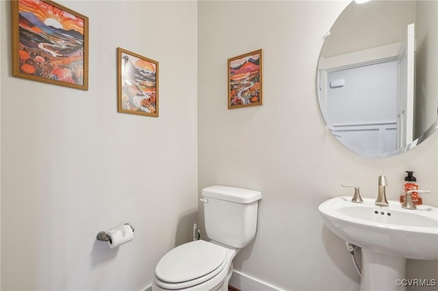 bathroom featuring toilet, baseboards, and a sink