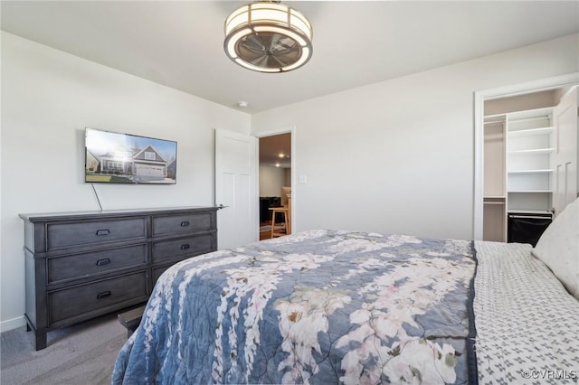 bedroom featuring a spacious closet, carpet flooring, and baseboards