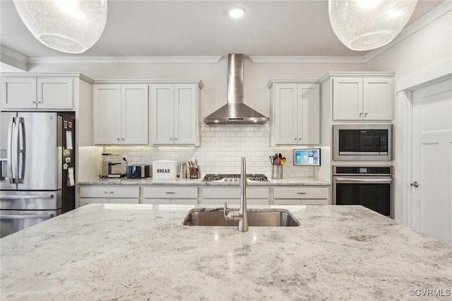 kitchen featuring stainless steel appliances, wall chimney range hood, a sink, and crown molding