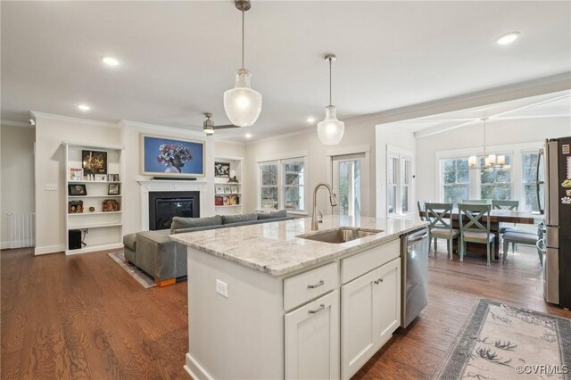 kitchen with light stone counters, stainless steel appliances, dark wood-style flooring, a sink, and a glass covered fireplace