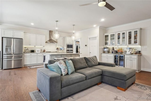 living area with light wood finished floors, beverage cooler, and ornamental molding