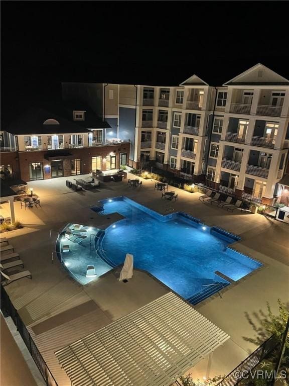 pool at night with a community pool and a patio