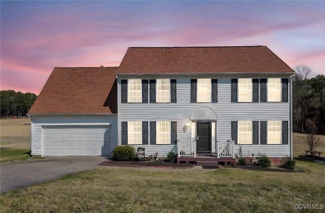 colonial house with an attached garage, a front lawn, and concrete driveway