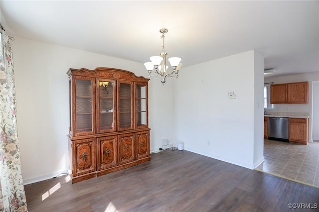 unfurnished dining area featuring baseboards, wood finished floors, and a notable chandelier