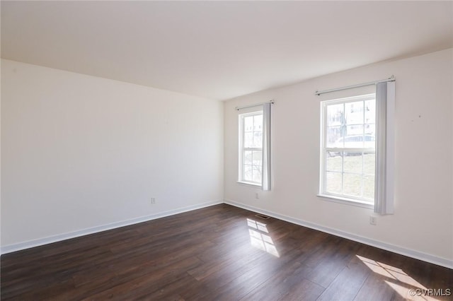 unfurnished room with baseboards and dark wood finished floors