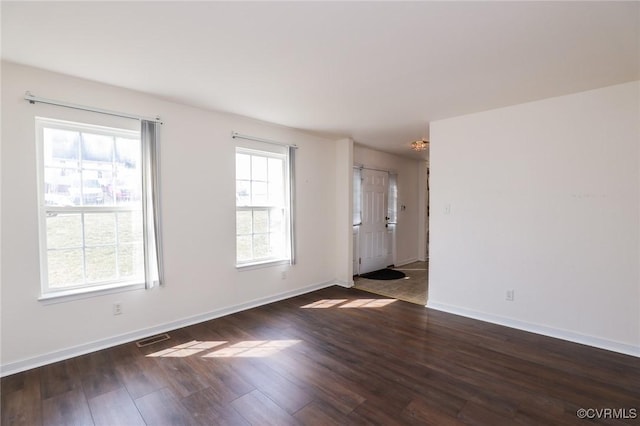 spare room with baseboards, visible vents, and dark wood-style flooring