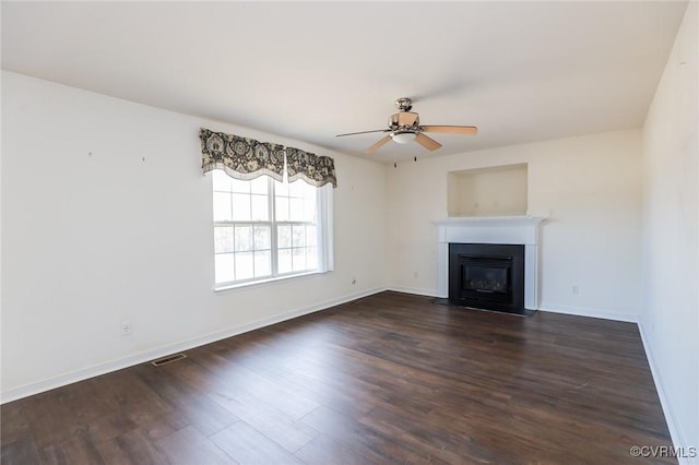 unfurnished living room featuring dark wood-style floors, a fireplace with flush hearth, baseboards, and a ceiling fan