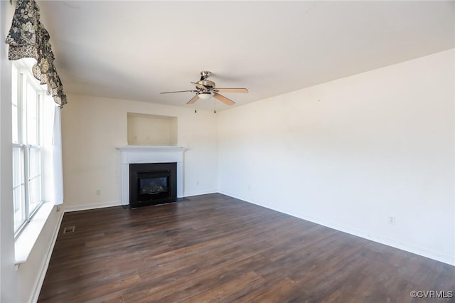 unfurnished living room featuring baseboards, visible vents, a fireplace with flush hearth, ceiling fan, and dark wood-type flooring