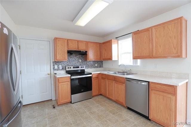 kitchen featuring under cabinet range hood, stainless steel appliances, a sink, light countertops, and decorative backsplash