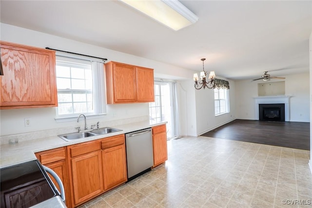 kitchen featuring a fireplace, light countertops, a sink, range, and dishwasher