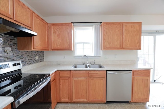 kitchen with light countertops, appliances with stainless steel finishes, a sink, and under cabinet range hood