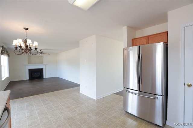 kitchen with a fireplace, appliances with stainless steel finishes, brown cabinets, decorative light fixtures, and an inviting chandelier