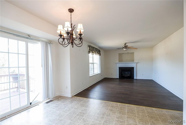 unfurnished living room with ceiling fan with notable chandelier, wood finished floors, a glass covered fireplace, and baseboards