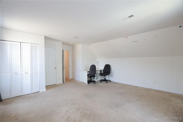 unfurnished office with baseboards, visible vents, vaulted ceiling, and light colored carpet