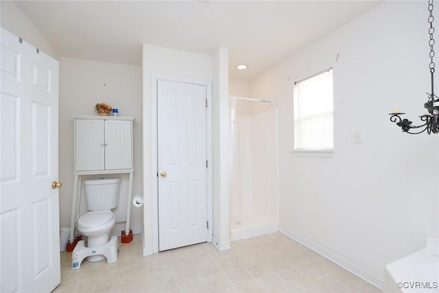 bathroom with toilet, a shower stall, and baseboards