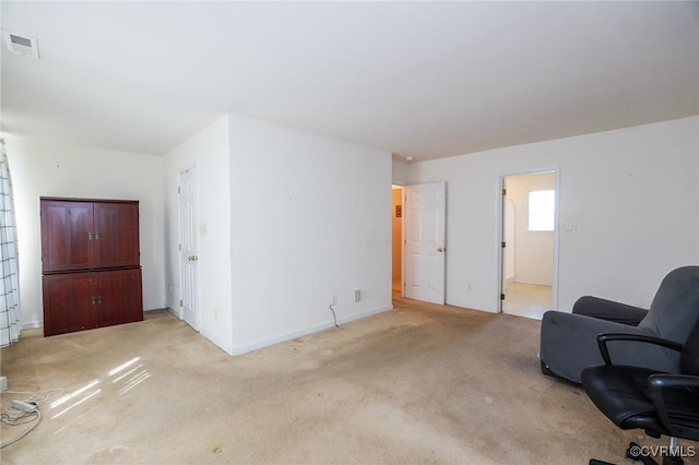 living area featuring baseboards, visible vents, and light colored carpet