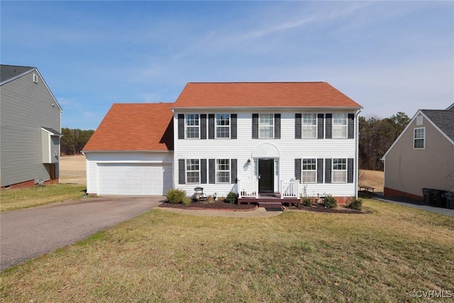 colonial inspired home featuring an attached garage, aphalt driveway, and a front yard