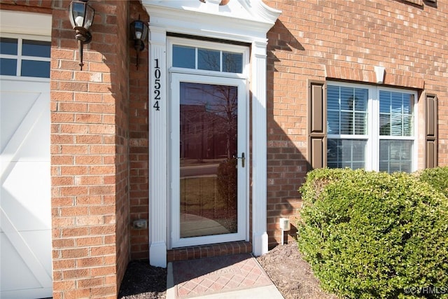 doorway to property featuring brick siding and an attached garage