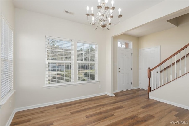 entryway featuring visible vents, stairway, an inviting chandelier, wood finished floors, and baseboards