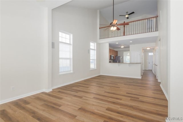 unfurnished living room featuring light wood-type flooring, ceiling fan, and baseboards