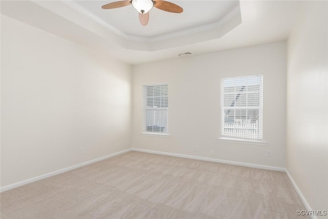 spare room featuring ornamental molding, a tray ceiling, light colored carpet, and baseboards