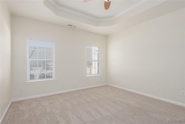 empty room featuring ceiling fan, a tray ceiling, carpet, and baseboards