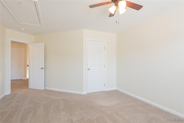 unfurnished bedroom featuring attic access, baseboards, ceiling fan, and light colored carpet