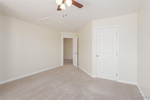 unfurnished bedroom with attic access, baseboards, a ceiling fan, and light colored carpet