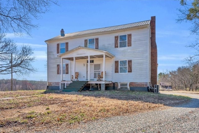 view of front of home featuring covered porch, metal roof, and a chimney