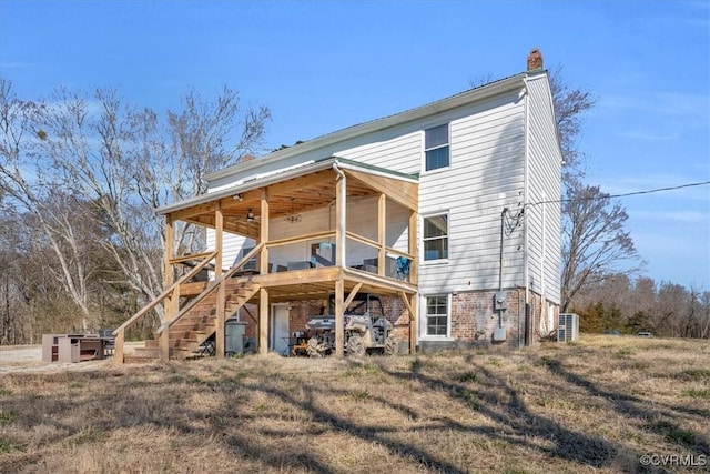 back of house featuring a chimney, stairway, and a ceiling fan